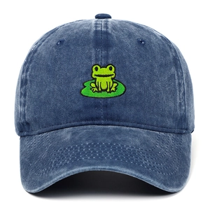 Detailed embroidery of a green frog on a leaf over blue washed denim baseball cap