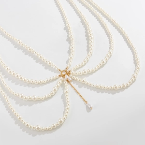 Detail of multi-layer pearl body chain with golden ring connector on white background