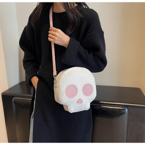 Detail of funny skull-shaped crossbody bag featuring pink accents and adjustable strap