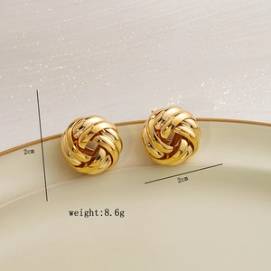 Detailed view of 2cm golden twisted rope hoop earrings weighing 8.6g on a ceramic tray