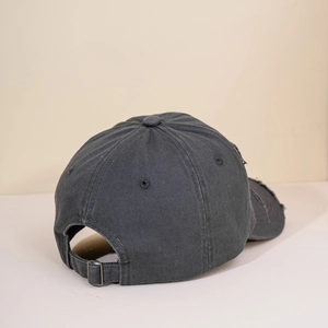 Detailed view of the washed dark grey baseball cap with worn holes and adjustable buckle