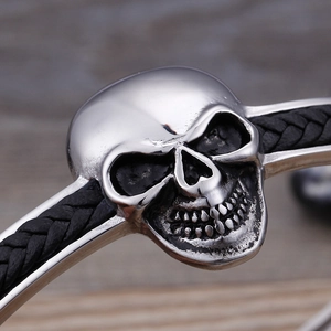 Makroaufnahme von Totenkopf-Charm aus Edelstahl am schwarzen geflochtenen Lederarmband