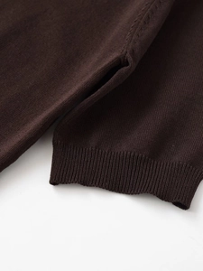 Close-up detail of dark brown knit sweater with ribbed cuffs and side split hem design