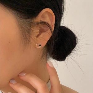 Close-up of minimalist black heart stud earrings in silver frame worn by a model