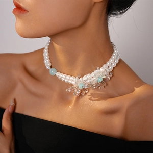Elegant double-layered faux pearl necklace with transparent floral charms on a model
