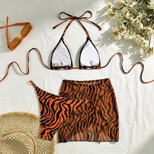 Detailed flat lay of tiger print three-piece bikini with mesh skirt and summer accessories
