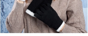 Detail of soft black knit gloves with white ribbed cuffs and matching scarf for winter