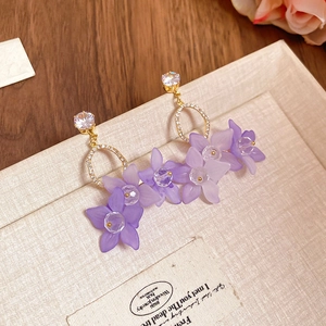 Macro detail of purple matte flower earrings with gold finish and zircon accents