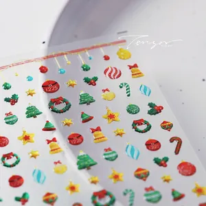 Macro shot of 3D Christmas nail stickers with trees, bells and glitter textures