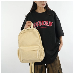 Detail of a large corduroy backpack in cream yellow held by a hand showing premium texture