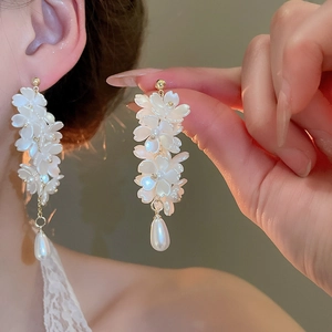 Detail of floral earrings with pearl pendants and gold metal accents for women