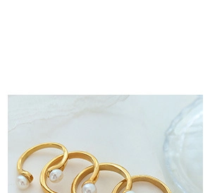Detailed view of multiple gold-plated rings featuring elegant white pearls on lace fabric