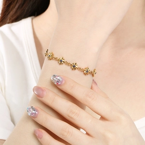 Elegante bracciale a fiori dorati con pietre blu indossato sul polso di una donna