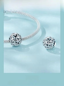 Detailed macro view of S925 sterling silver scroll pattern charm with cubic zirconia