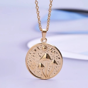 Macro view of gold stainless steel pendant with embossed mushroom, moon and stars engraving