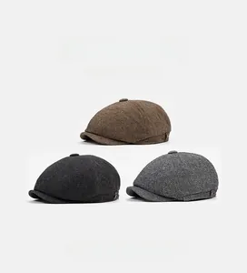 Multiple colors of herringbone newsboy caps including brown and grey on a clean background