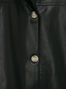 Detail of black coated leather jacket showing button and textured pebble grain material