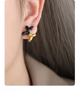 Detail shot of a minimalist black and gold balloon dog earring on a fashion model