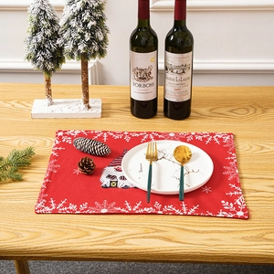 Red Christmas placemat featuring a festive gnome and snowflakes on a wooden table setup