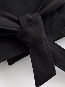 Détail du nœud de ceinture sur un gilet noir en sergé montrant la texture du tissu