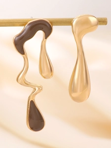 Detail of asymmetrical earrings with gold waterdrop and brown enamel wave design