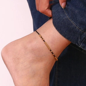 Close-up of 18K gold-plated stainless steel bead anklet with black cord on ankle
