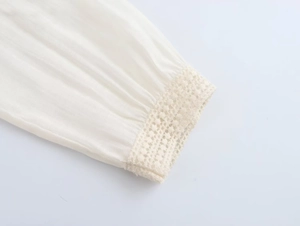 Close-up of beige crochet lace trim on white cotton linen long sleeve cuffs