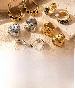 Detailed view of titanium steel heart earrings and C-shaped zircon rings in gold and steel