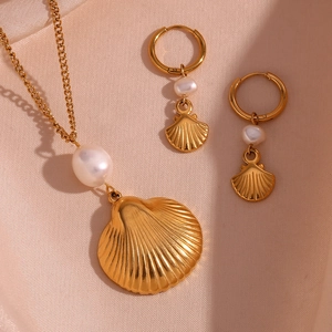 Detail of 18K gold shell jewelry set with earrings and necklace on beige silk