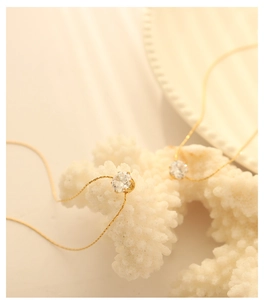Macro shot of 18K gold plated thin chain necklace with round zircon on white coral decor