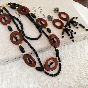 Detail of crystal tassel necklace and earrings set with brown resin rings on fabric