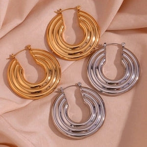 Detailed view of textured gold and silver hoop earrings on champagne silk fabric