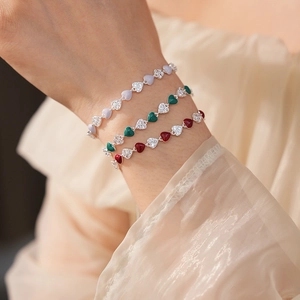 Close-up of stacked vintage heart bracelets with colorful enamel and zircon on wrist