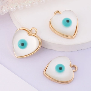Detailed view of three white heart-shaped evil eye pendants with golden metal edges