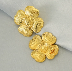 Détail macro de boucles d'oreilles tournesol en acier doré avec pétales texturés