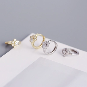 Detailed macro view of gold and silver cat paw earrings with heart shaped zircon stones