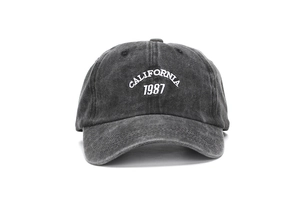 Dettaglio del ricamo bianco California 1987 su un cappello da baseball grigio finto vintage