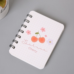 Close-up of A7 spiral notebook with pink cherry and floral patterns on a grid cover