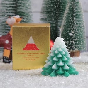 Green Christmas tree scented candle with snow effect in a gold gift box with holiday decor