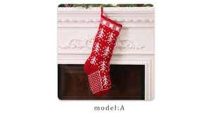 Knitted red Christmas stocking with snowflake patterns hanging on a white fireplace mantle
