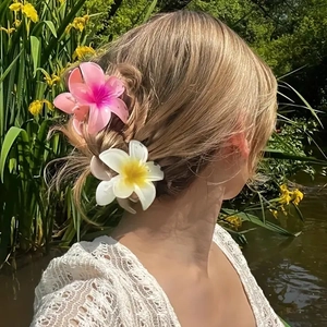 Detailed view of pink and white gradient plumeria flower hair claws worn by a model