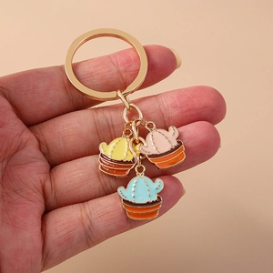 Detail of three colorful enamel cactus pendants on a gold keychain with pink and blue accents