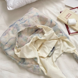 Close-up of internal zipper pocket and white bow embroidery on gradient canvas tote