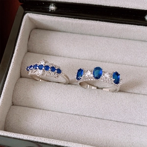 Détail de bagues ovales en argent et zircone dans un écrin avec pierres bleues et blanches