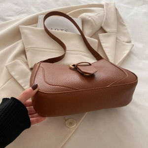 Detail of brown lychee texture leather shoulder bag with metallic ring buckle and flap