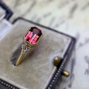 Vintage style gold engagement ring featuring a large emerald cut pink gemstone and diamonds