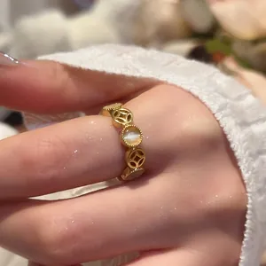 Artistic gold ring with opal and coin pattern shown on hand with a cozy sweater background