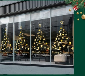 Golden Christmas tree window decals with festive stars and ornaments on a glass storefront