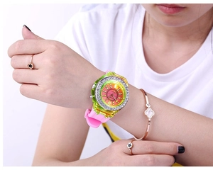Detail of neon yellow rhinestone watch paired with clover bracelet on woman's wrist