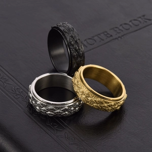 Rotating stainless steel evil eye rings in gold, silver, and black on a black notebook